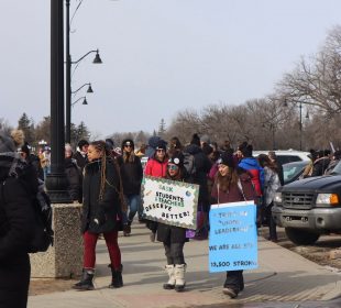 A crowd of teachers picket at the Saskatchewan legislature earlier this year. Two signs are visible, one reads, “SASK STUDENTS AND TEACHERS DESERVE BETTER!”