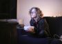 A photo of a person sitting on a couch, with a bowl of snacks, intently watching TV.