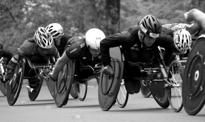 A photo of athletes in racing wheelchairs competing against each other.