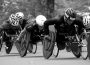 A photo of athletes in racing wheelchairs competing against each other.