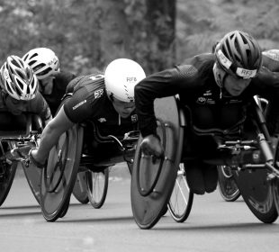 A photo of athletes in racing wheelchairs competing against each other.