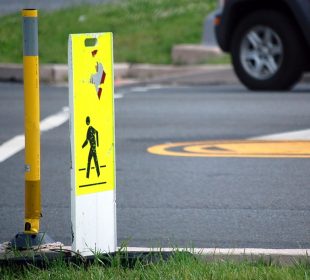 A pedestrian crossing sign on the side of a road.