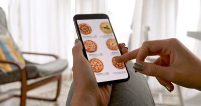 A hand holding a phone screen, open to a food delivery app.