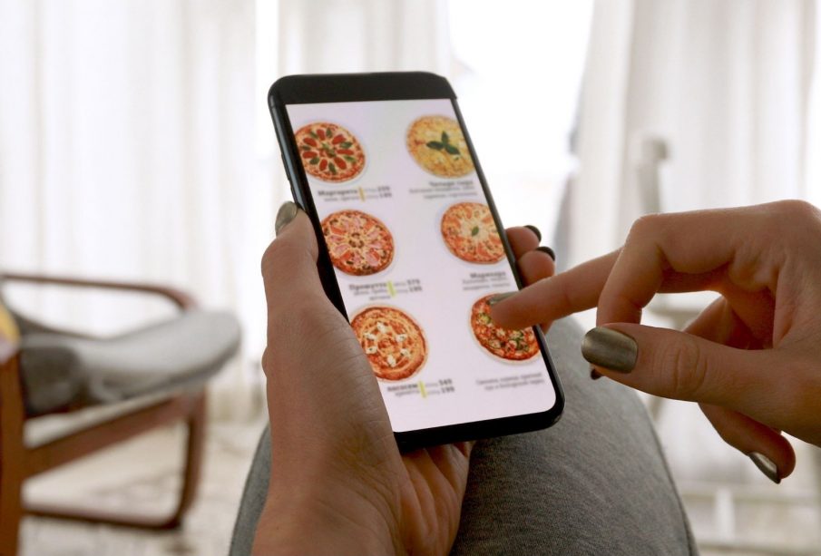 A hand holding a phone screen, open to a food delivery app.