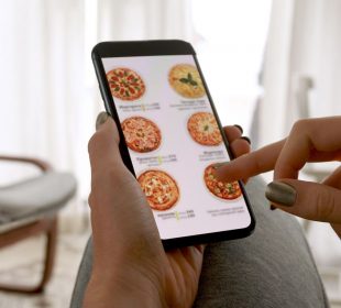 A hand holding a phone screen, open to a food delivery app.