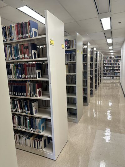 Stacks of books are shown on shelves in Archer Library