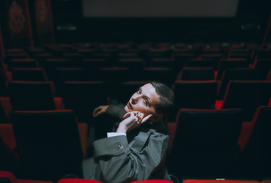 A photo of the artist Elena Erin, sitting, looking at the camera.