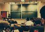 A photo of a classroom from the back of the class, the blackboard is filled with math.