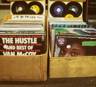 Two boxes of old records sit side-by-side in the street.