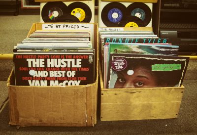 Two boxes of old records sit side-by-side in the street.