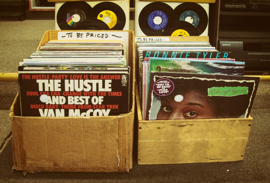 Two boxes of old records sit side-by-side in the street.