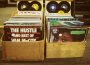 Two boxes of old records sit side-by-side in the street.
