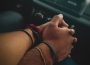 Close up of two individuals holding hands in a car with a blurred stereo in the background