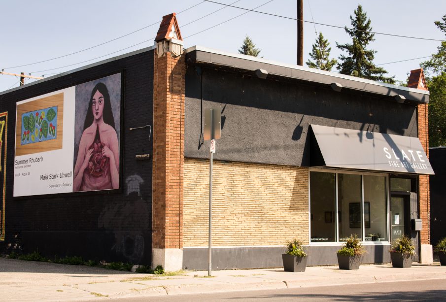 The Slate Art Gallery building from an angle, displaying both the entrance and the billboards for Summer Rhubarb and the next show, Maia Stark’s Unwell.