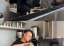 This image shows a person standing behind a counter. The kitchen is industrial with clean metal, and the person is wearing glasses and a kitchen apron. The top image shows the person shaking bubble tea in a metal cup, and the bottom image shows them pouring it into a glass.