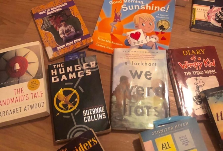 This photo shows a spread of books laid out on the floor. These books range from children’s books, all the way to young adult novels. Some of the classics listed include Diary of A wimpy Kid, The Hunger Games, and The Handmaid’s Tale.