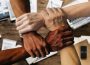 This is a photo of four arms of varying skin tones holding onto each other. Each hand is clutching a wrist, creating a perfect square, or an endless connection.