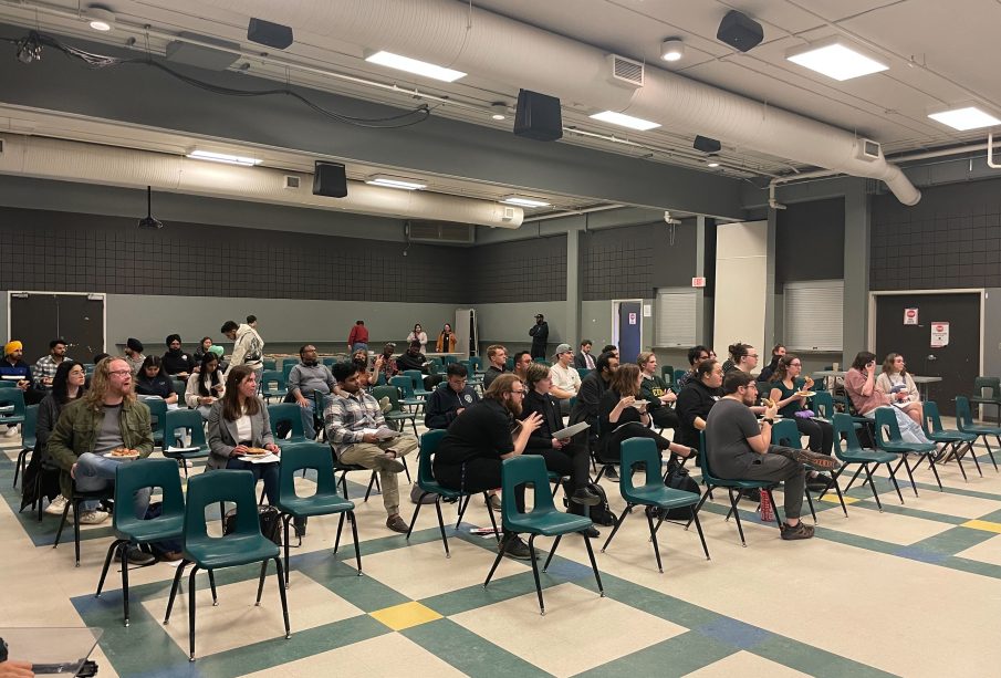 Students eat pizza while they wait for URSU to fix the microphone.