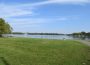 A panoramic shot of Wascana Lake, with green grass and a view of the lake waters.