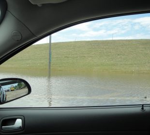 A view from a car window, showing accumulation of water on the streets.