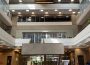 A well-lit, midday photo taken in the ‘pit’ of the Administration Humanities Building facing the main north doors, showing the full height of the building from carpeted floor to the president’s office at the top.