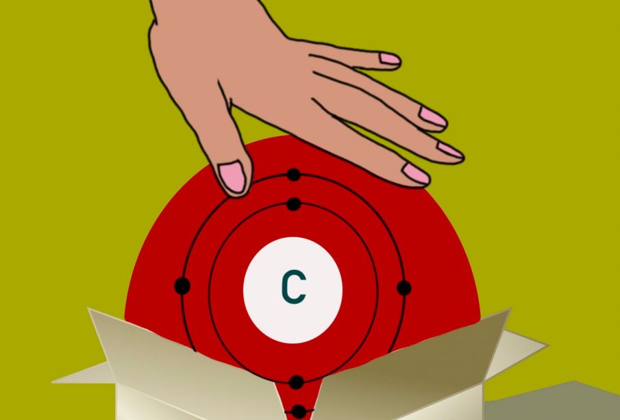 A hand comes down from the top of the image to push the element carbon into a storage box.