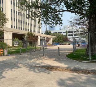 A photo taken from the street to the west of Regina’s city hall which shows the lawn space fully blocked off by fences which have “NO TRESSPASSING” signs attached to them. 
