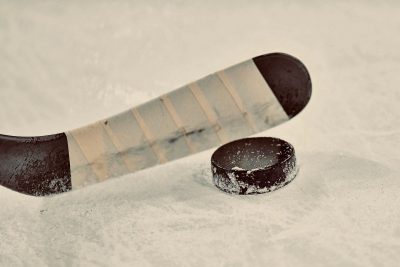 A hockey stick positioned right above a hockey puck.