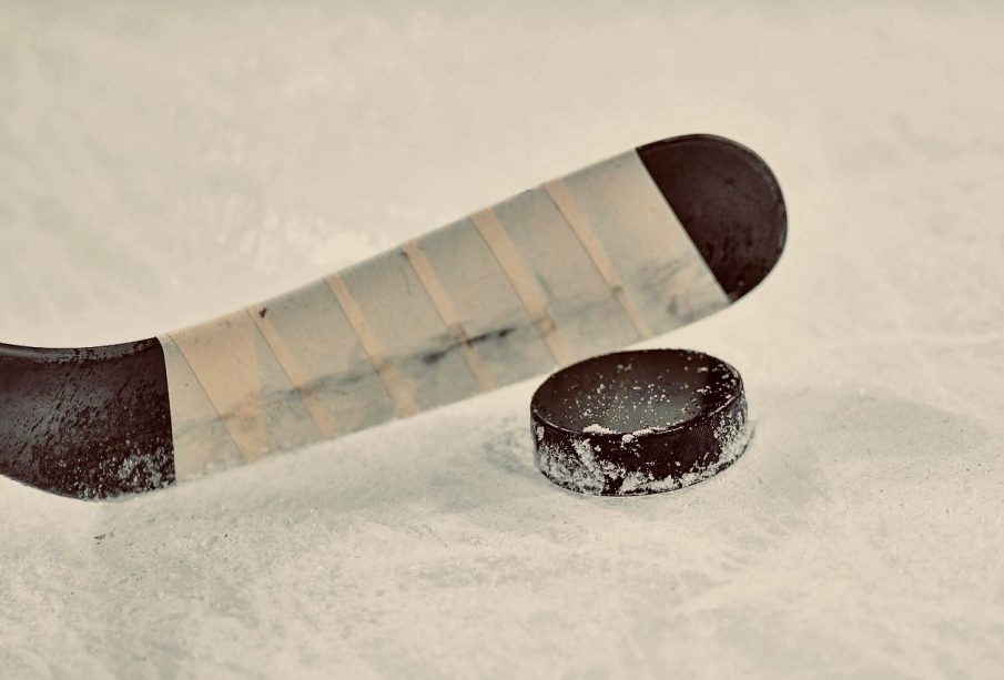 A hockey stick positioned right above a hockey puck.