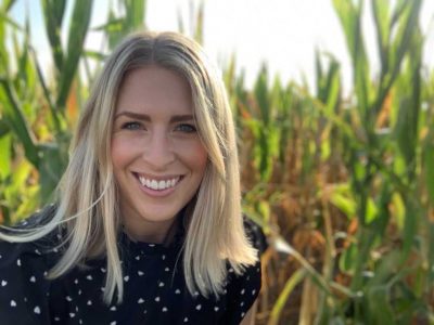 A photo of Megz Reynolds standing in the backdrop of a farm.