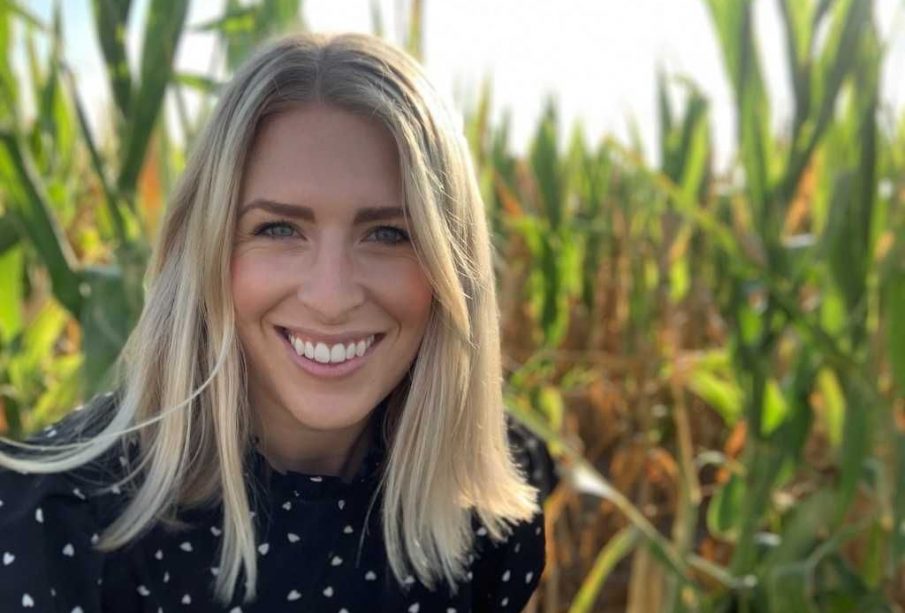 A photo of Megz Reynolds standing in the backdrop of a farm.