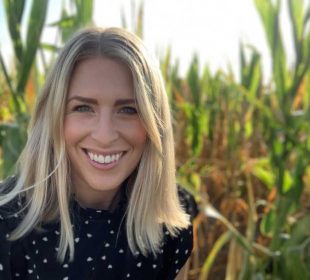 A photo of Megz Reynolds standing in the backdrop of a farm.