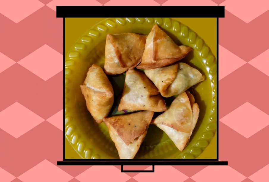 An image of samosas on a film screen pulled over a deep pink background with lighter pink diamond chains running widthwise.