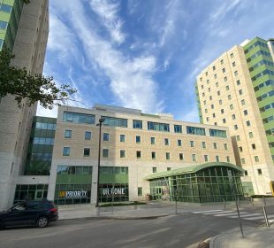 A photo depicts a University of Regina student residence against a dramatic blue, cloud-streaked sky.