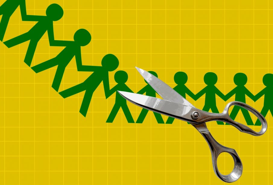 A yellow background with a green chain of paper-cutouts in the shape of people holding hands with stainless-steel scissors in the foreground.