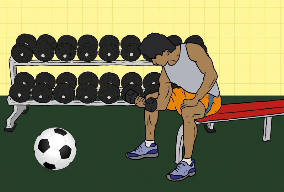 A young person doing curls with a dumbbell while a soccer ball rests in front of them.