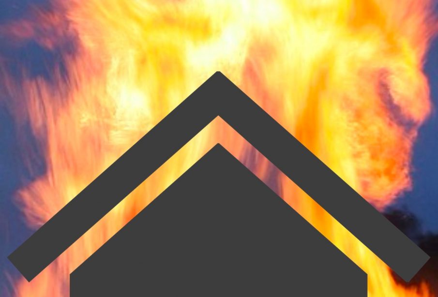 The black outline of a home is backlit by destructive flames.