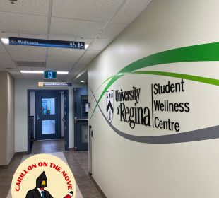 A photo of a wall with the words “University of Regina Student Wellness Centre” on it. 