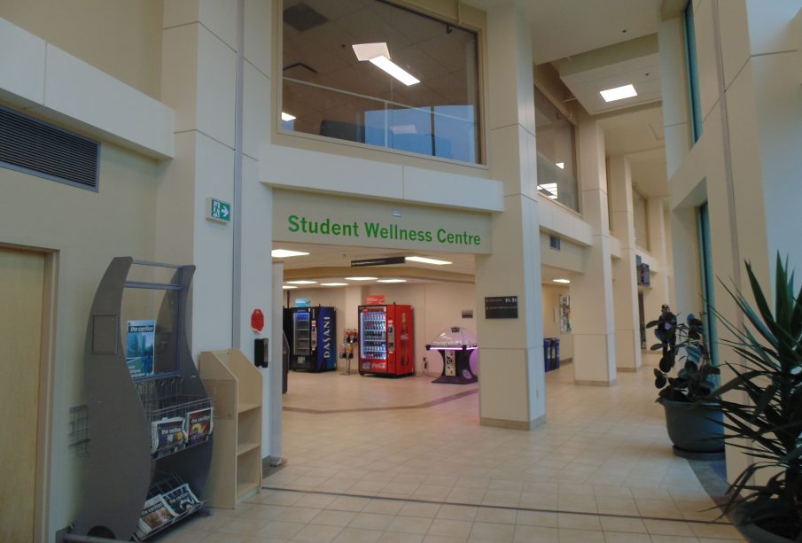 A photo of a corridor, with some vending machines visible. A sign says “Student Wellness Centre.”