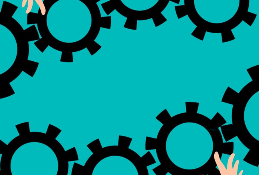 Several different hands juggle and fit together gears like those found in clockworks.