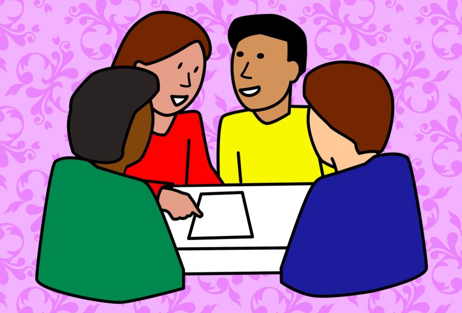 Four friends sitting around a table, talking. They all look like they are from different parts of the world.