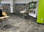 One section of a public library branch, with some desks and chairs. The wall is lined with bookshelves.