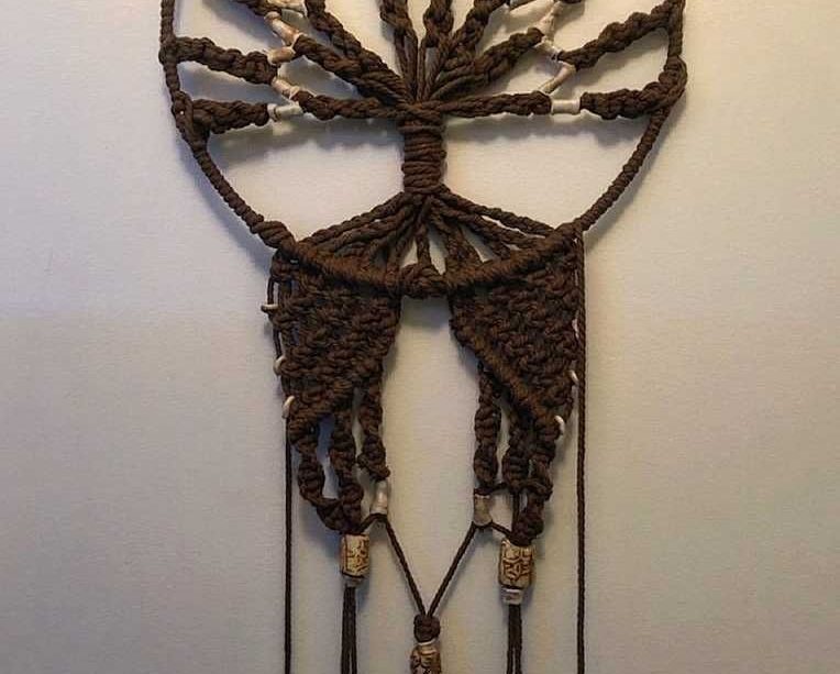 A beautiful macramé craft hanging up on a wall.
