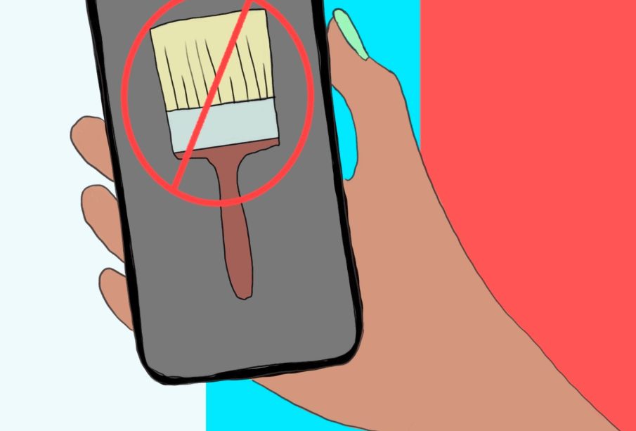 Someone holds a phone in their right hand that shows a paintbrush on the screen covered by a red circle with a line crossing through it diagonally. The background is three vertical stripes coloured white, blue, and red.