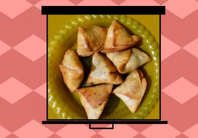 An image of samosas on a film screen pulled over a deep pink background with lighter pink diamond chains running widthwise.