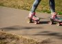 A person wearing multi-coloured roller-skates glides down a walkway bordered by grass.  