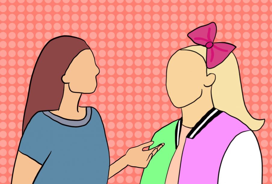 A long-haired brunette has raised an upturned hand in conversation with a long-haired blonde who has a giant pink bow attached in front of a high-ponytail. The brunette is wearing a blue T-shirt and the blonde is wearing a pink shirt with a bomber jacket on top. The jacket has a green right side and a pink left side with white sleeves.