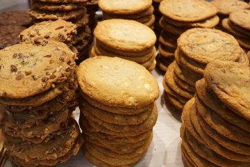 Many stacks of cookies that look like they contain nuts and chocolate chips.