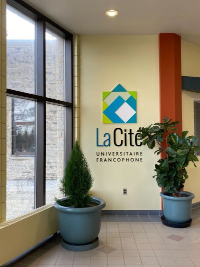 Potted plants sit on the floor by the wall sign for La Cité.