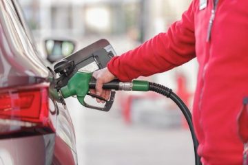 A person’s arm is shown filling up a car tank with fuel.